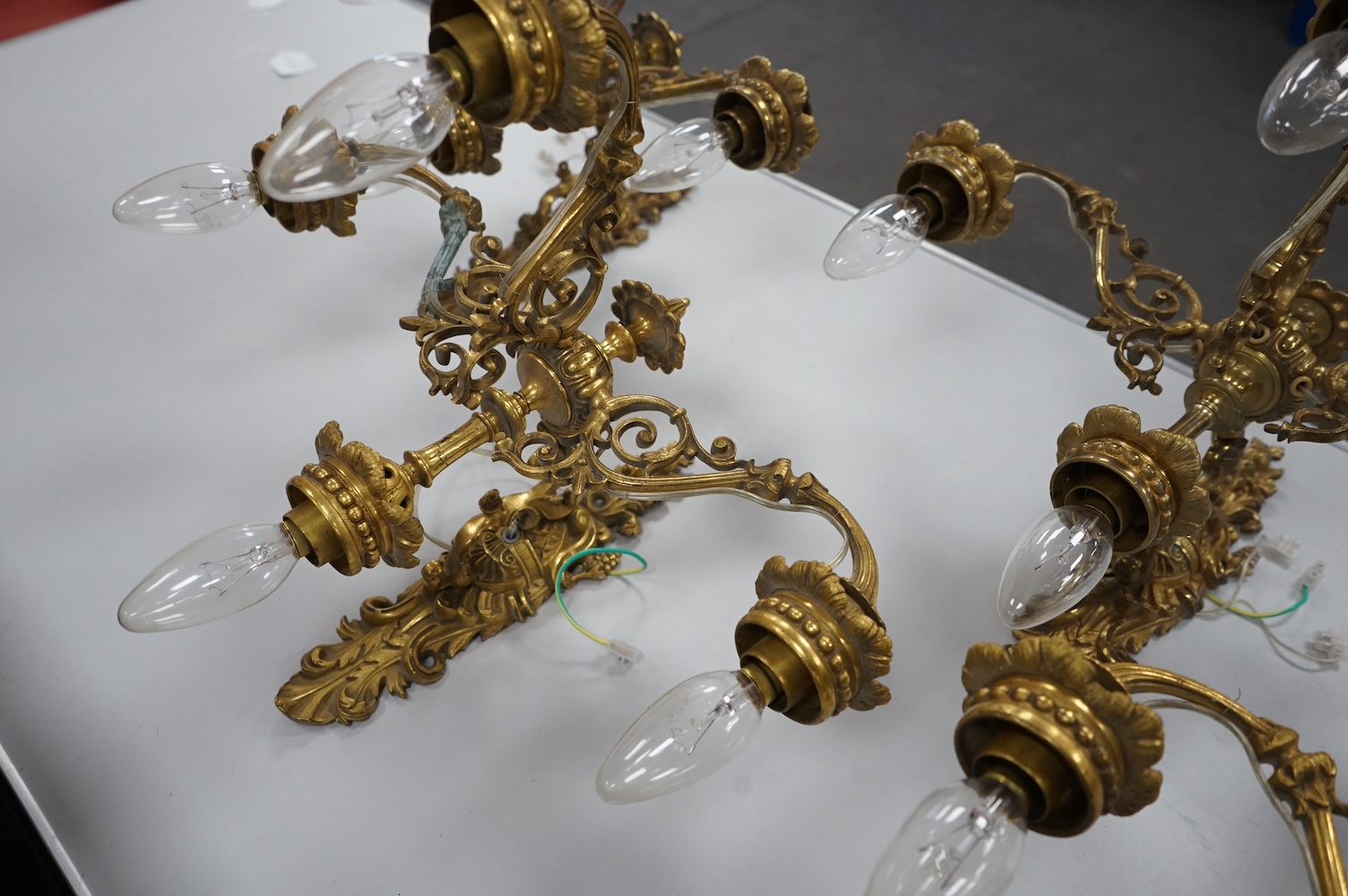 A set of four Baroque style, three branch brass wall lights. 44cm wide x 28cm high. Condition - good